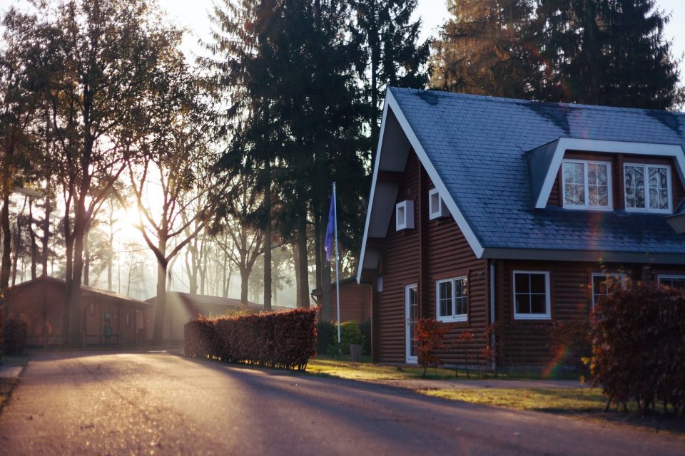 a house by a roadside with trees surrounding it