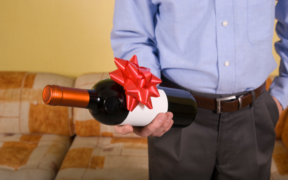 a man in a suit holding a gift-wrapped bottle of wine