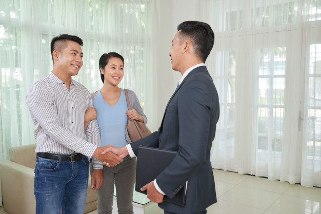 a couple shaking hands with a real estate agent wearing a suit