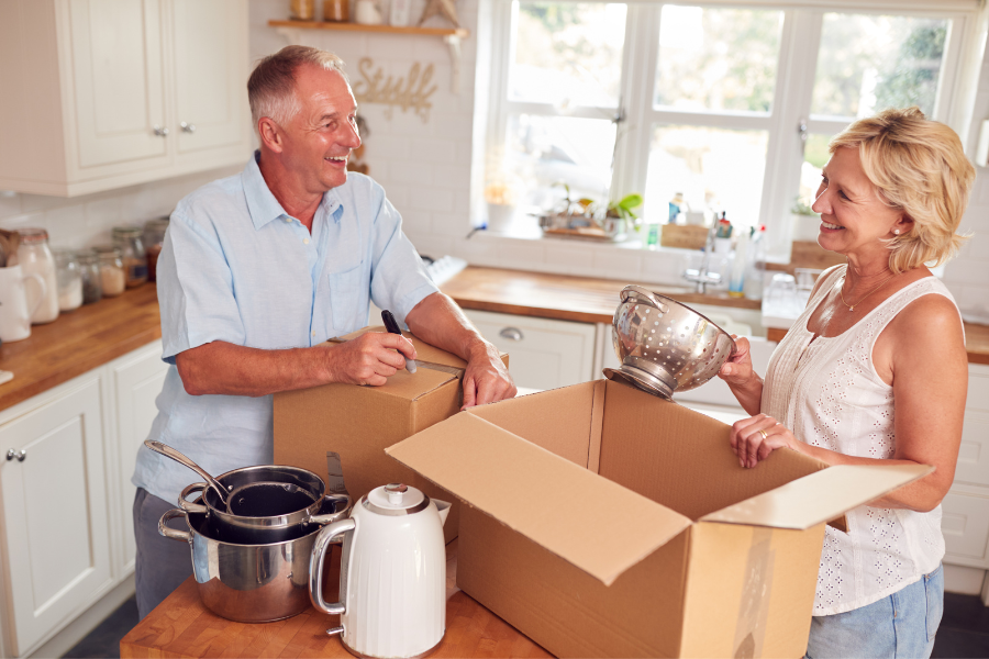 older couple downsizing home and unpacking boxes in the kitchen