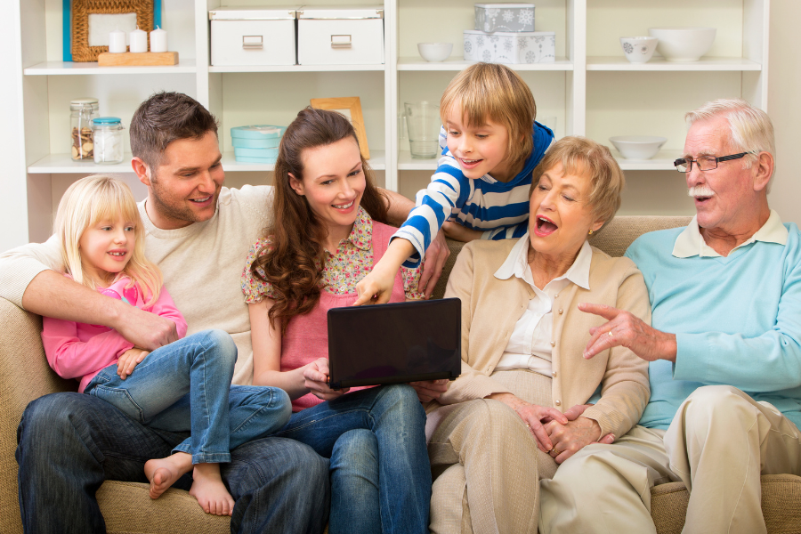 a family with parents, kids, and grandparents laughing on the couch