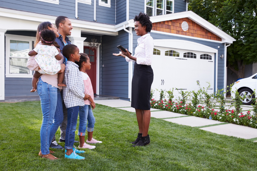 a family speaking to a woman real estate agent outside a house
