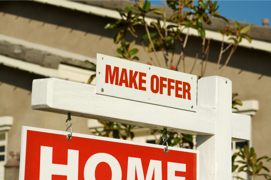 a for sale board saying make offers outside a house