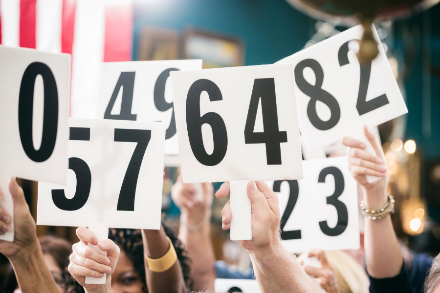 a group of people holding up auction numbers