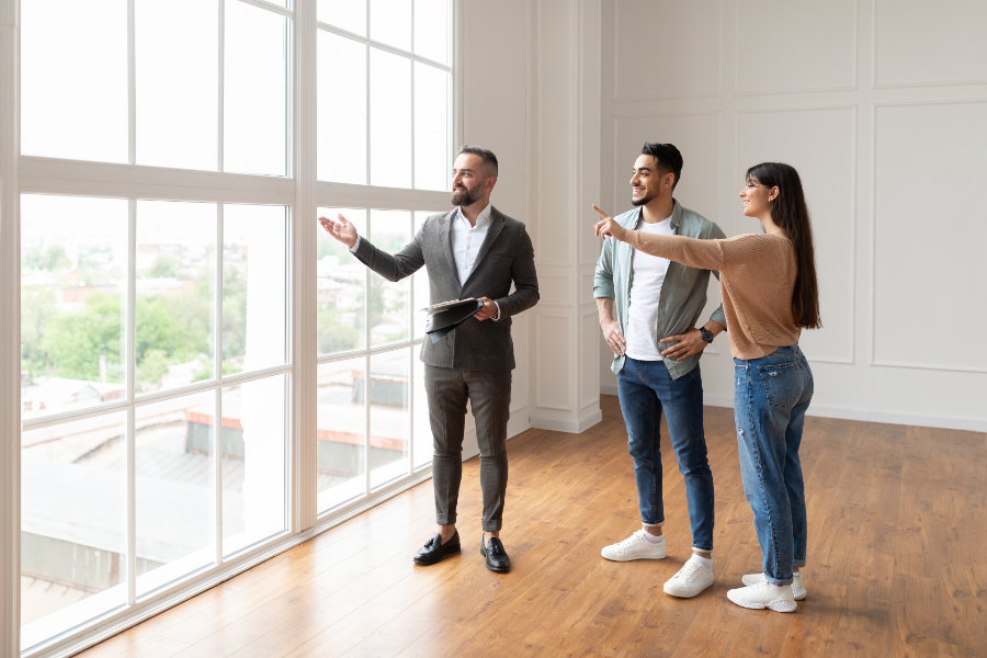 a millennial couple being shown around an empty property by a realtor