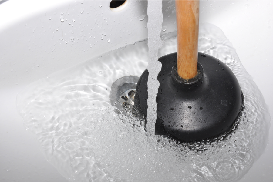 a plunger in a sink with a clogged drain at home