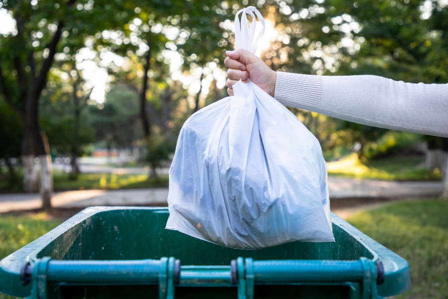 a person placing trash into a trash can in a backyard