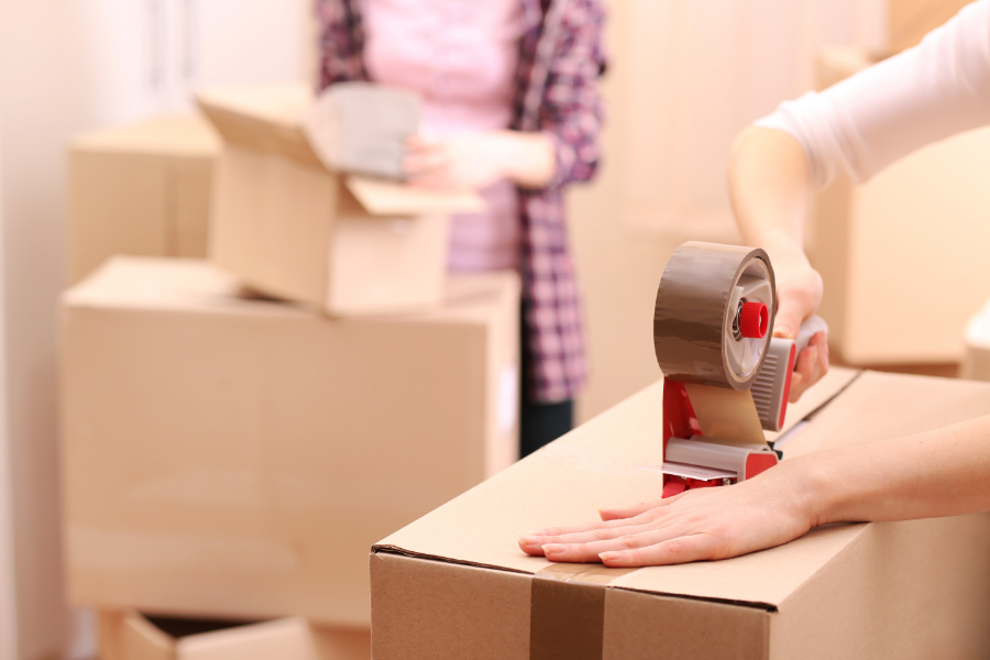 two people packing and taping up boxes