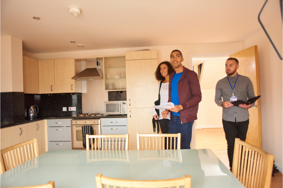 a couple being shown around a property by a real estate agent