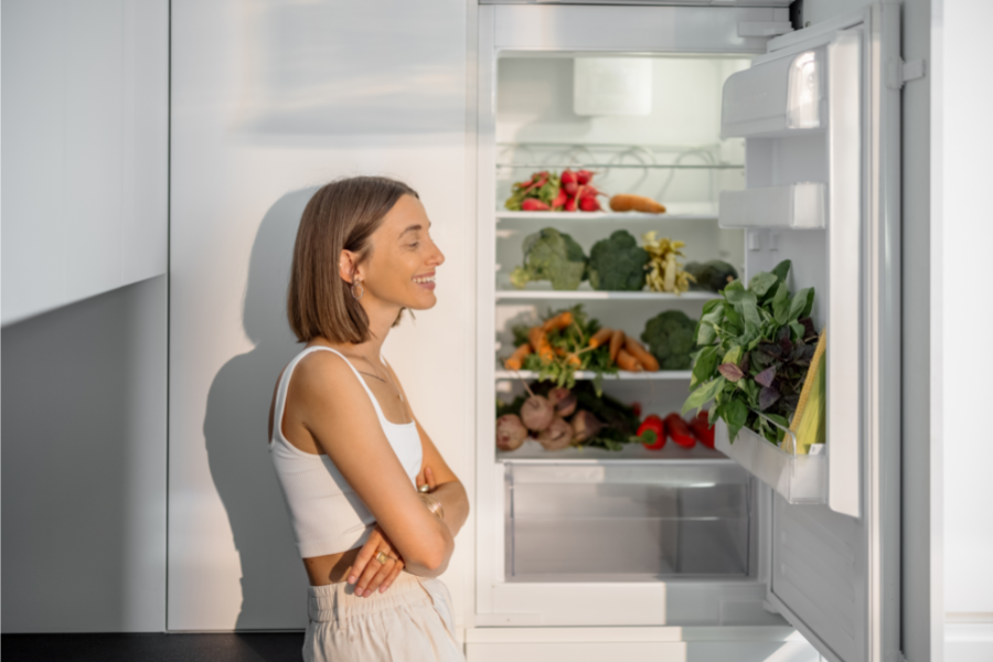 a woman staring into a small open fridge 