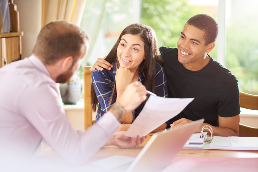 a young woman and man talking over paperwork with a man