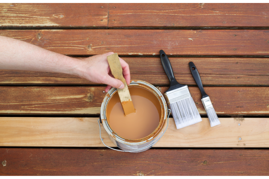 a person painting a wood deck