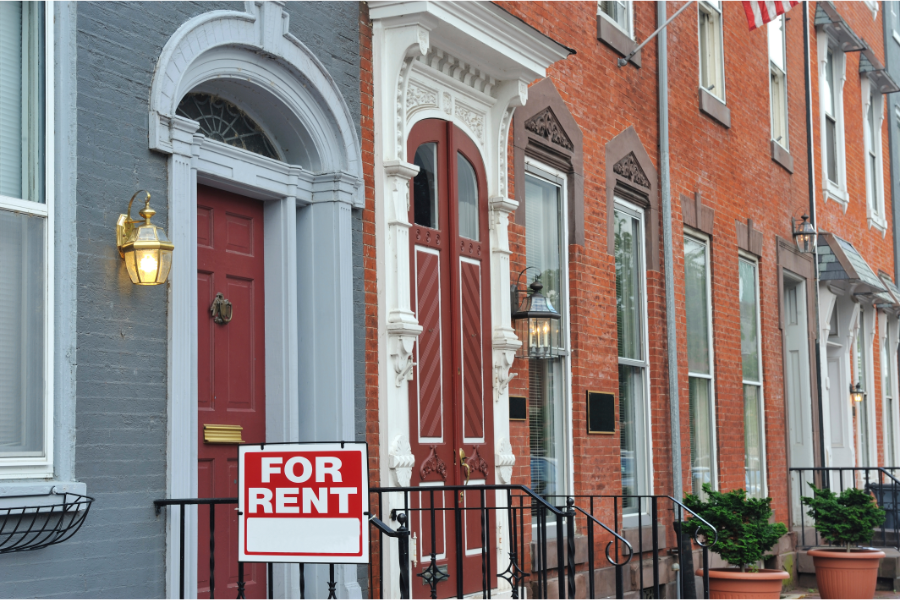 a row of philadelphia houses with a for rent board outside